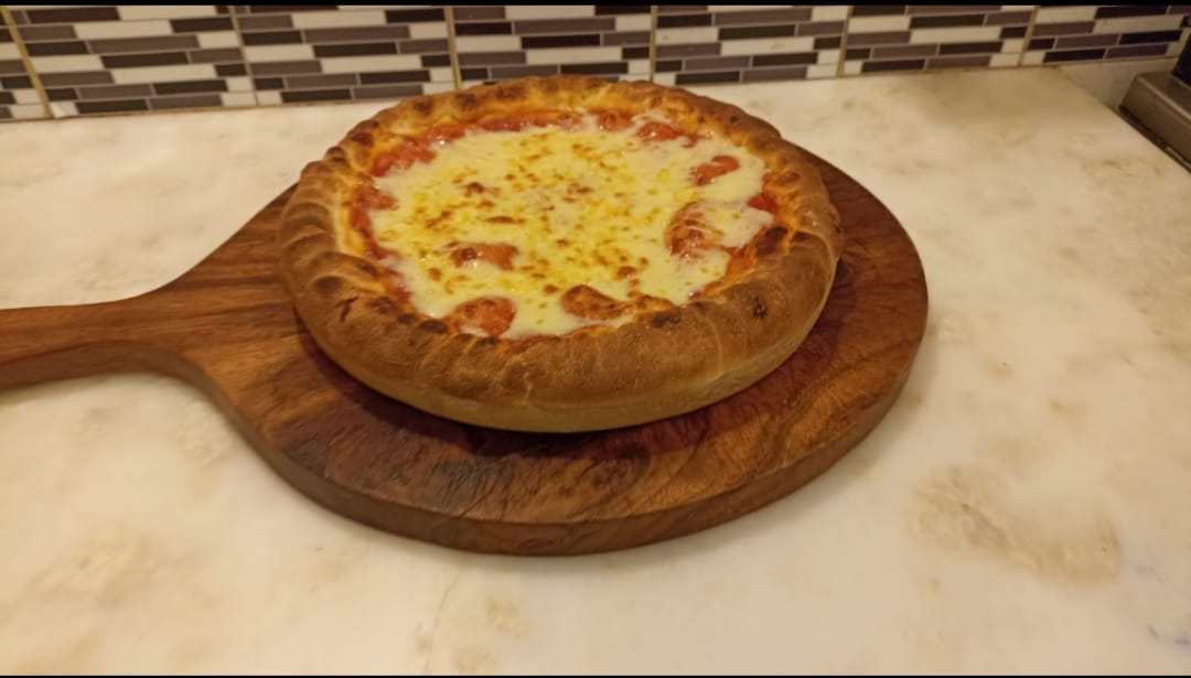 Pizza artesanal recién horneada en Montevideo, en tabla de madera
